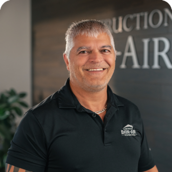 Employé de Construction Bon-Air posant devant le logo de l’entreprise