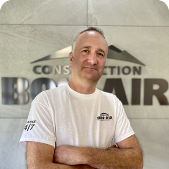 Homme en t-shirt blanc devant un mur d'entreprise